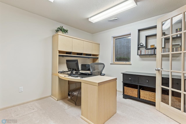 office featuring built in desk, baseboards, light colored carpet, and a textured ceiling