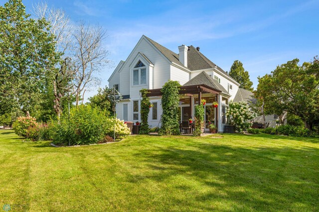 back of property with a pergola, a lawn, and a chimney
