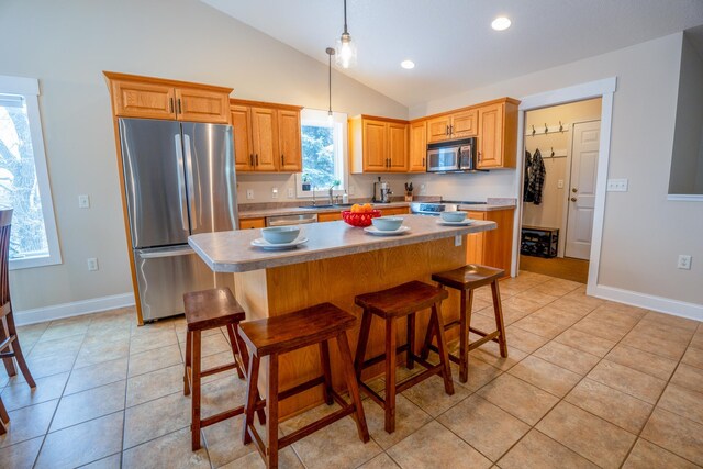 122 Ridge Rd, New London, MN 56273 - kitchen with appliances with stainless steel finishes, vaulted ceiling, a kitchen island, light tile patterned floors, and a breakfast bar