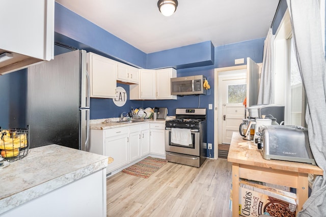 560 Stryker Ave, Saint Paul, MN 55107 - kitchen with white cabinetry, light countertops, stainless steel appliances, and a sink