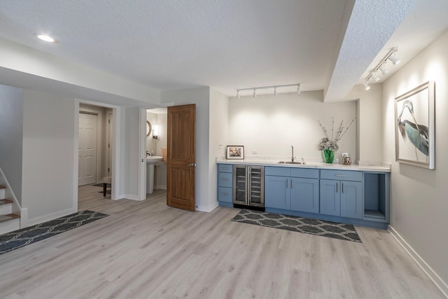 bar with wine cooler, indoor wet bar, rail lighting, and a sink