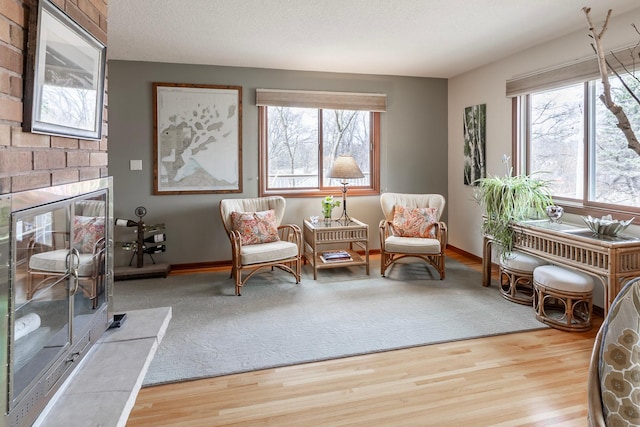 living area with baseboards, a large fireplace, and wood finished floors