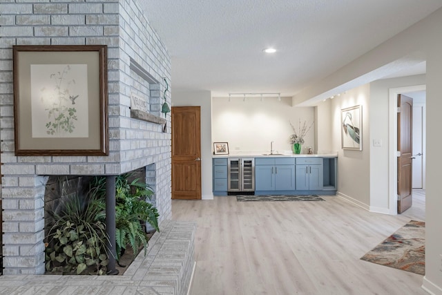 30 Interlachen Ln, Tonka Bay, MN 55331 - indoor wet bar with light wood-style floors, a fireplace, beverage cooler, a textured ceiling, and recessed lighting