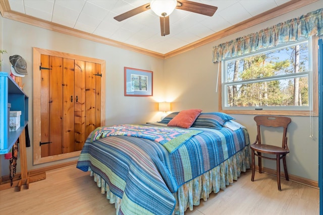 bedroom featuring wood finished floors, crown molding, a ceiling fan, and baseboards