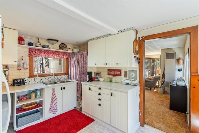 kitchen with a sink, light countertops, open shelves, and tasteful backsplash