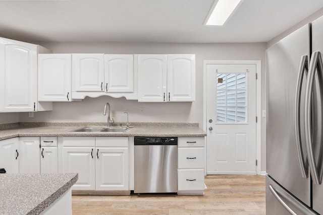 kitchen with white cabinets, light countertops, appliances with stainless steel finishes, a sink, and light wood-type flooring