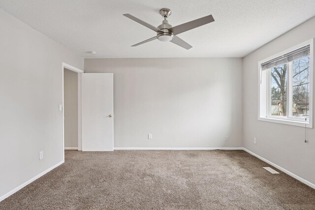 carpeted spare room featuring baseboards, a textured ceiling, visible vents, and a ceiling fan