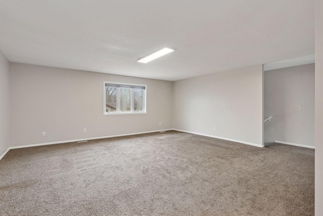 carpeted spare room featuring baseboards and a textured ceiling