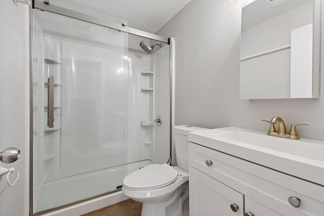 full bath featuring toilet, vanity, wood finished floors, and a shower stall