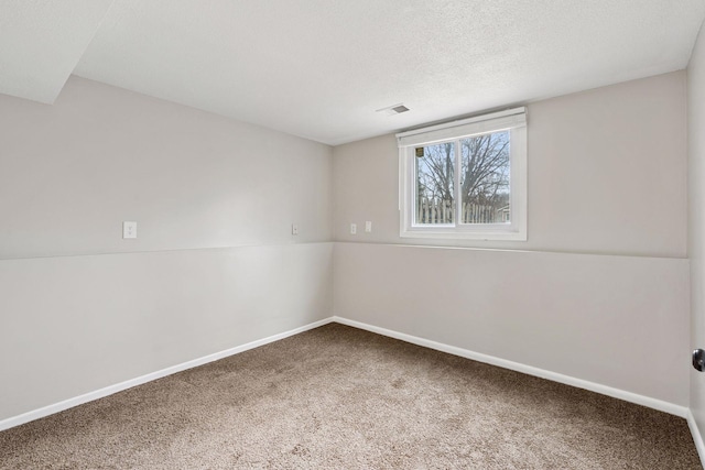 spare room featuring carpet floors, baseboards, visible vents, and a textured ceiling