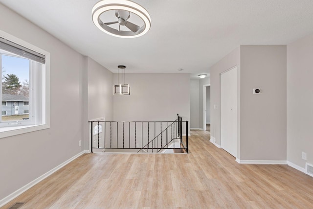 unfurnished room with a ceiling fan, baseboards, light wood finished floors, and visible vents