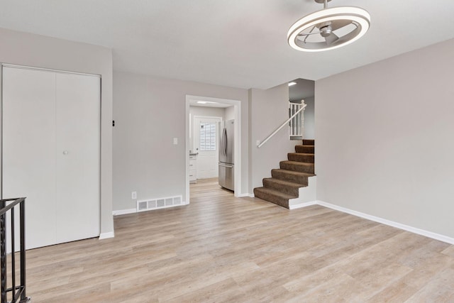 unfurnished living room featuring light wood-type flooring, a ceiling fan, baseboards, and visible vents