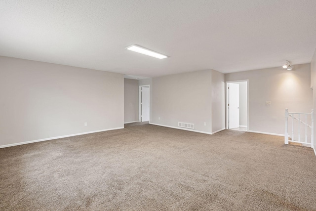 carpeted empty room with a textured ceiling, baseboards, and visible vents