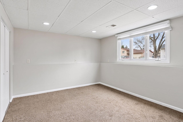 empty room with baseboards, carpet flooring, visible vents, and a paneled ceiling