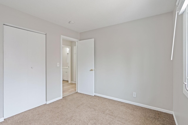 unfurnished bedroom with a closet, baseboards, and light colored carpet