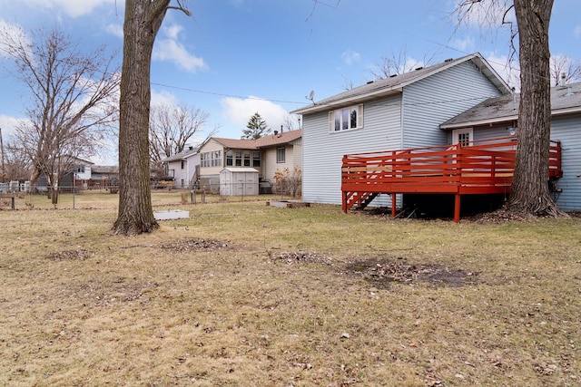 rear view of property featuring a lawn, a wooden deck, and fence