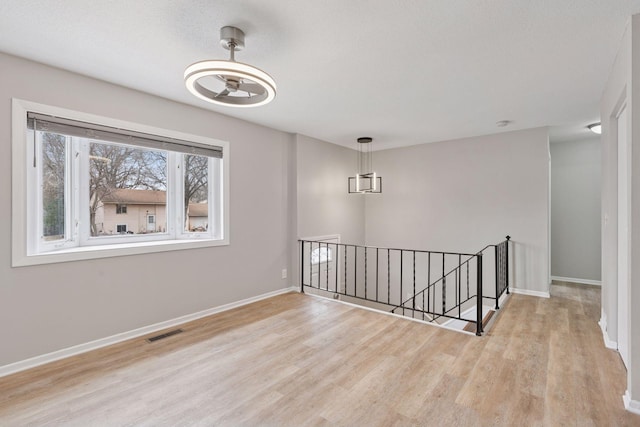 empty room with wood finished floors, baseboards, and visible vents