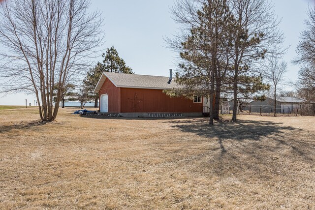48987 Tamarac Dr, Scambler Twp, MN 56572 - view of home's exterior featuring fence, a garage, a shingled roof, an outdoor structure, and a yard