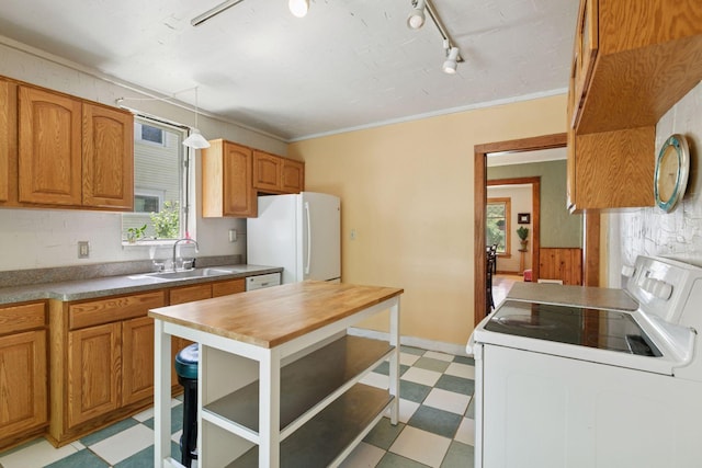 kitchen with light flooring, white appliances, a sink, track lighting, and brown cabinetry