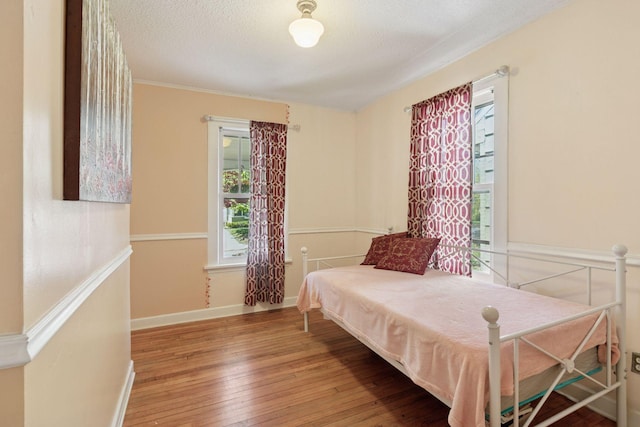 bedroom with wood-type flooring, a textured ceiling, and baseboards