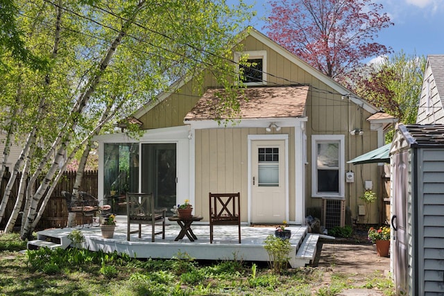rear view of property featuring a wooden deck, fence, and central AC unit