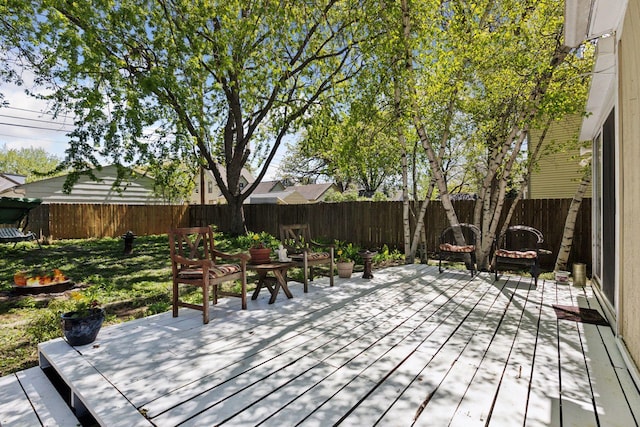 wooden terrace with a fenced backyard