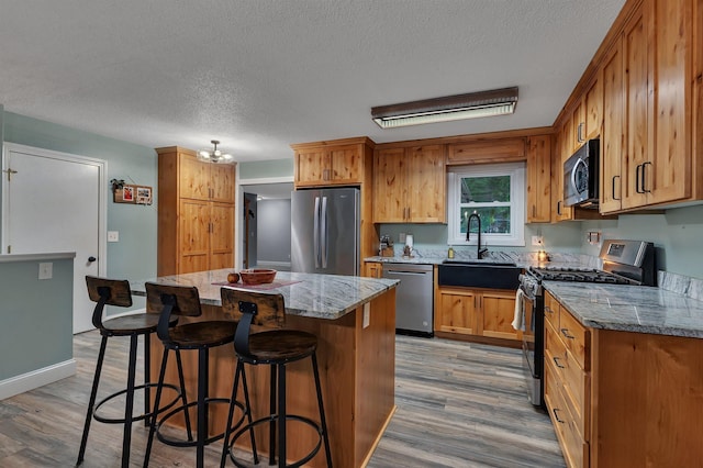 257 Elm Dr, Foley, MN 56329 - kitchen with stainless steel appliances, a textured ceiling, wood finished floors, a center island, and a breakfast bar area