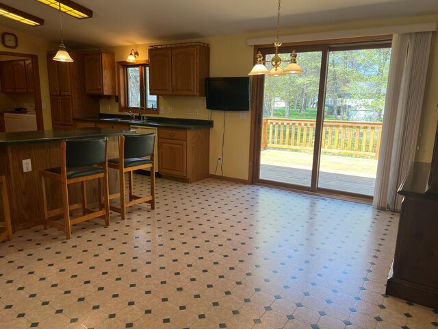 14289 Memorywood Dr, Baxter, MN 56425 - kitchen with dark countertops, hanging light fixtures, light floors, and brown cabinetry