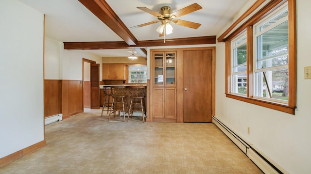 interior space with a ceiling fan, a baseboard heating unit, brown cabinetry, and beam ceiling