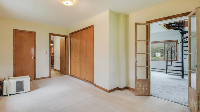 unfurnished bedroom with baseboards, carpet flooring, heating unit, and a closet