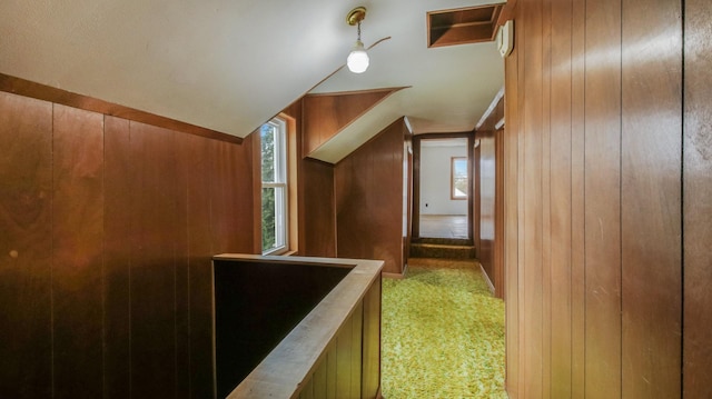 additional living space with wooden walls, light colored carpet, and vaulted ceiling