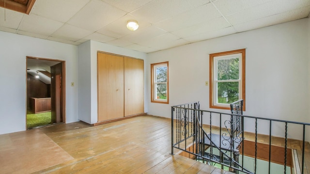 unfurnished bedroom with a closet, light wood-style flooring, and a paneled ceiling