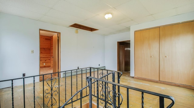 interior space featuring a paneled ceiling, wood finished floors, and an upstairs landing