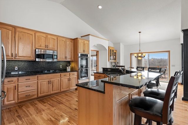 707 Bergman Ct NW, Isanti, MN 55040 - kitchen featuring a kitchen breakfast bar, backsplash, light wood-style floors, appliances with stainless steel finishes, and a sink