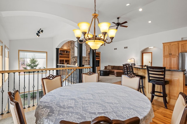 707 Bergman Ct NW, Isanti, MN 55040 - dining room with light wood-style floors, ceiling fan with notable chandelier, arched walkways, recessed lighting, and lofted ceiling