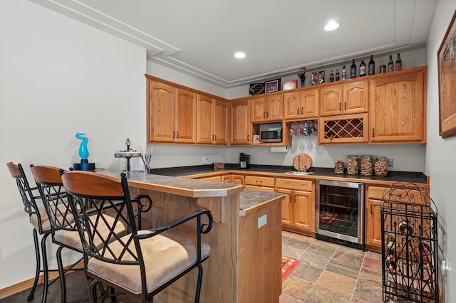 707 Bergman Ct NW, Isanti, MN 55040 - kitchen with a kitchen breakfast bar, a peninsula, stainless steel microwave, dark countertops, and beverage cooler