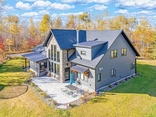 back of house featuring a patio, roof with shingles, stone siding, a yard, and a sunroom