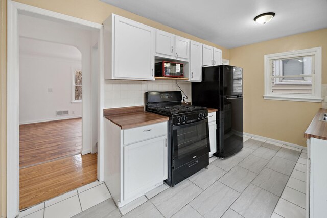 1119 6th St E, Saint Paul, MN 55106 - kitchen with visible vents, white cabinets, black appliances, backsplash, and light tile patterned flooring