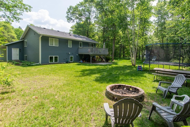 18885 Maryville Rd, Brainerd, MN 56401 - rear view of property with a trampoline, a fire pit, a wooden deck, and a yard