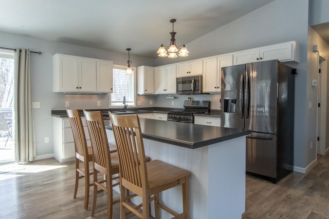 18885 Maryville Rd, Brainerd, MN 56401 - kitchen with stainless steel appliances, dark countertops, a chandelier, white cabinets, and wood finished floors