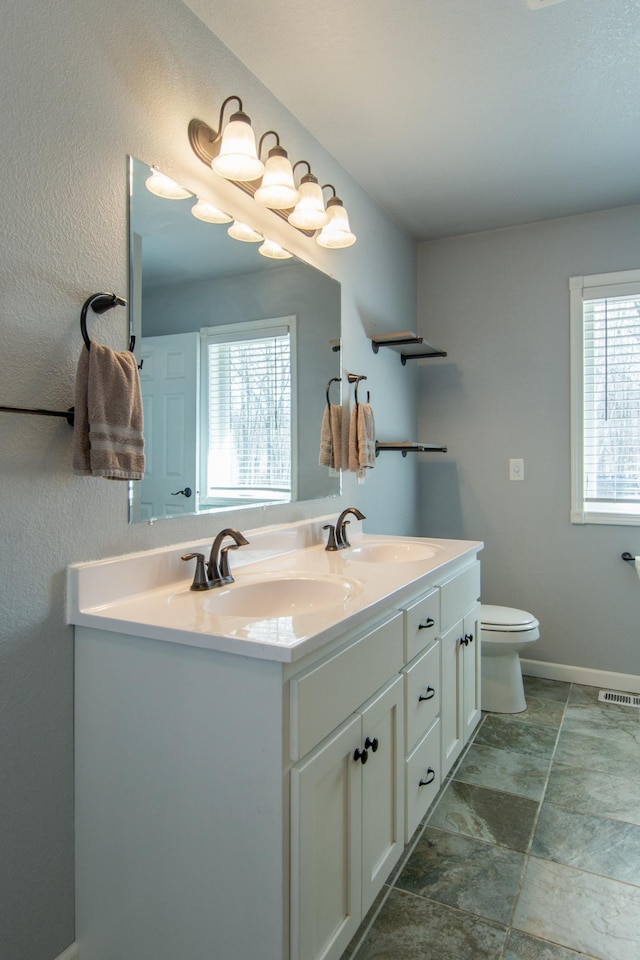 18885 Maryville Rd, Brainerd, MN 56401 - bathroom featuring double vanity, toilet, and baseboards