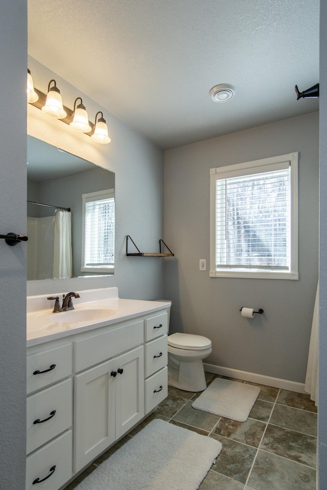 18885 Maryville Rd, Brainerd, MN 56401 - full bathroom with vanity, toilet, baseboards, a shower with curtain, and stone finish floors