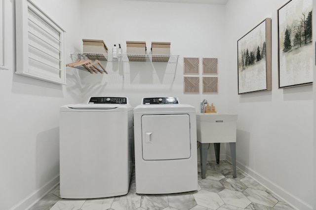 clothes washing area with independent washer and dryer, marble finish floor, laundry area, and baseboards