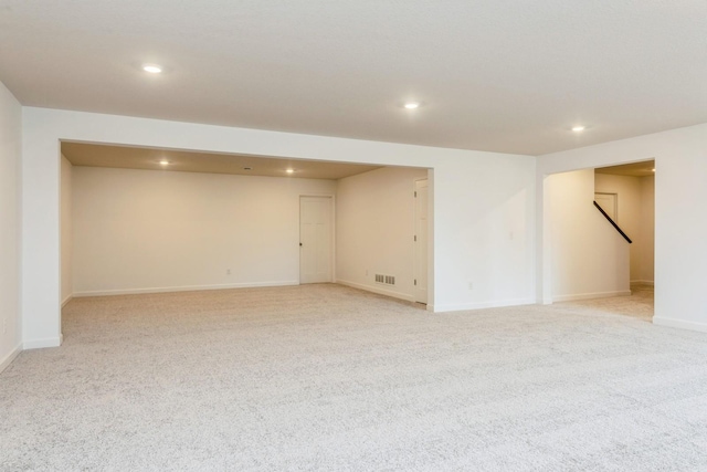 finished below grade area with visible vents, baseboards, recessed lighting, and light carpet