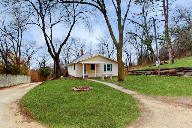 view of front of home with fence, a chimney, and a front yard