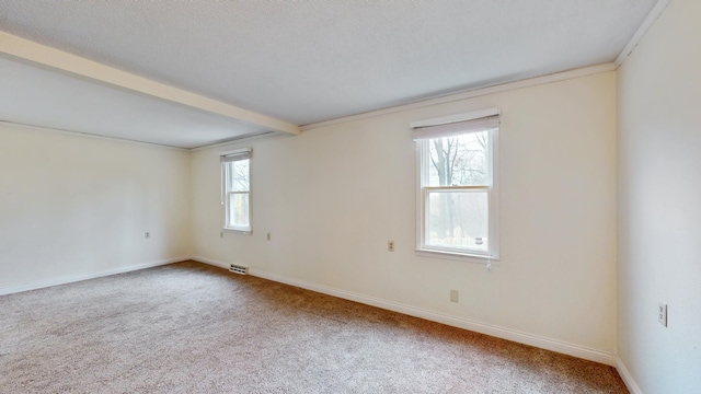 carpeted empty room featuring visible vents, beam ceiling, and baseboards
