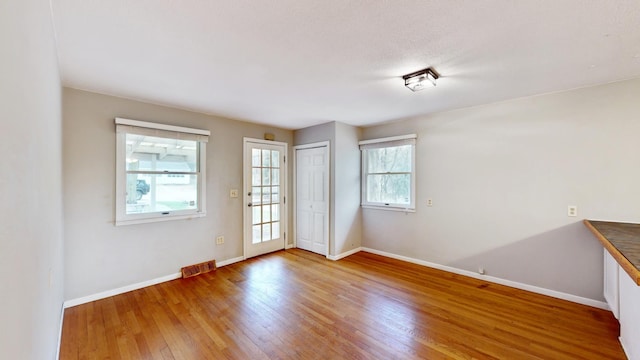 empty room with baseboards, visible vents, and wood finished floors