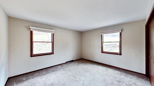 carpeted empty room with a textured ceiling and baseboards