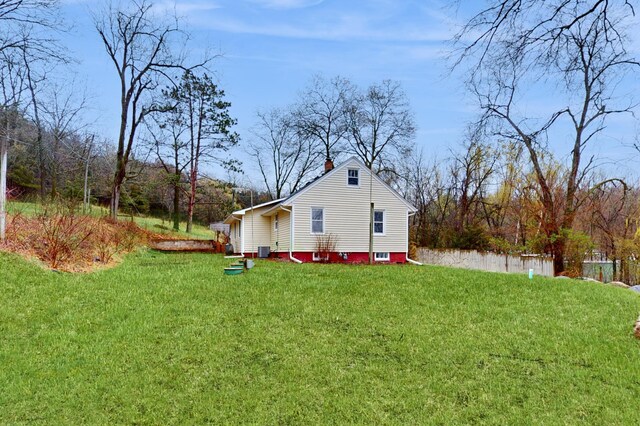view of side of home with a lawn, a chimney, and central AC