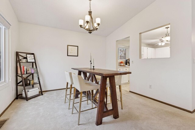 dining space with light colored carpet, baseboards, and vaulted ceiling